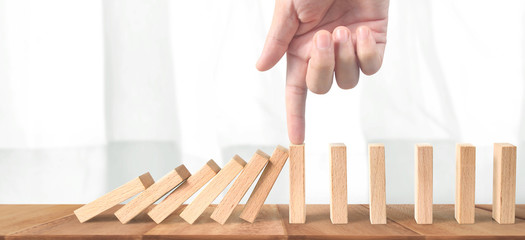 Hand stopping the Domino effect stopped by unique