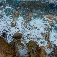 waves of the Mediterranean rush to the hot rocky beach on the Greek island of Crete