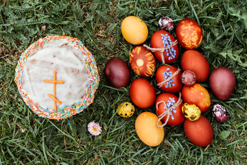 Easter background, Easter cakes and multi-colored chicken and quail eggs on bright natural grass background.
