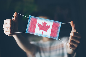 medical mask in hands of man, with the flag of  Canada painted. Copy space
