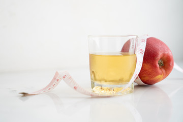 Apple and apple juice wrapped with measure tape  on white marble surface. Concept for fruit nutrition and diet food.