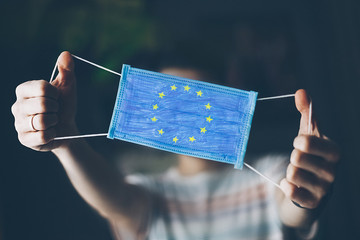 medical mask in hands of man, with the flag of  European Union painted. Copy space