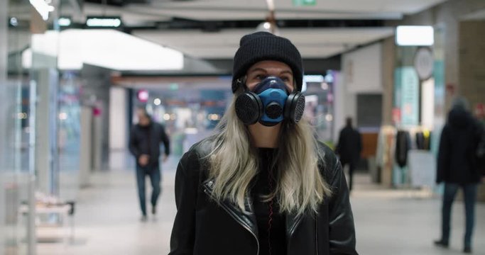 A young woman walking at a shopping mall wearing a protective face mask.