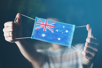 medical mask in hands of man, with the flag of Australia painted. Copy space