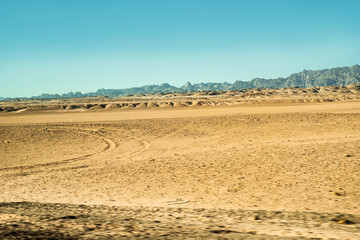 Fototapeta premium Safari in Egypt Sinai, travel of tourists in the Sahara desert.Road in the desert. Yellow sand and blue sky.