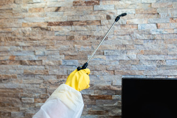 Exterminator in work wear spraying pesticide with sprayer.