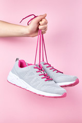 Running sports shoes on pink background, Pair of fashion stylish sneakers on hand