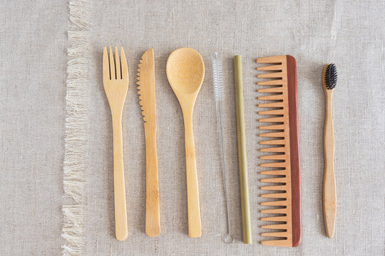 Eco friendly travel set , knife, fork, spoon, bamboo straw ,wood hair brush and toothbrush on natural linen background.  Zero Waste essentials
