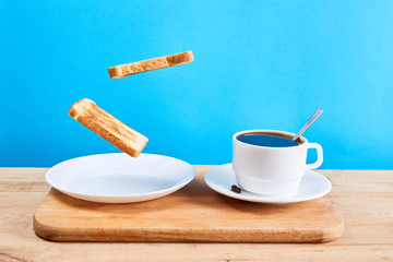 Fresh traditional breakfast with crispy toasts and cup coffee or tea on blue background. Levitation food concept.
