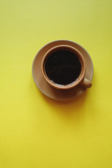 cup of coffee on yellow background with notepad