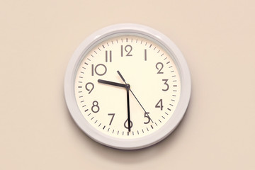 White round wall clock on a pink wall. Half past nine.