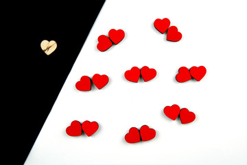 A lot of red hearts placed by couples on white background and a wooden one on black background. Concept of love and loneliness, isolation. Flat lay.