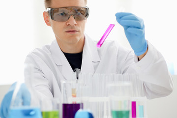 Male chemist holds test tube of glass in his hand overflows a liquid solution of potassium...