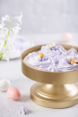 Obraz na płótnie Canvas Easter dessert Mini Pavlova Birds Nests with colorful eggs candy on a light background. Meringue Cookies. Festive Food recipe. Confectionery, bakery concept. Easter greeting card. Copy space