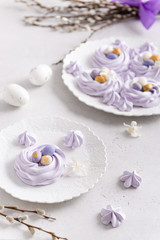 Obraz na płótnie Canvas Easter dessert Mini Pavlova Birds Nests with colorful eggs candy on a light background. Meringue Cookies. Festive Food recipe. Confectionery, bakery concept. Easter greeting card.