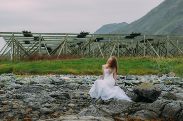 Fototapeta na wymiar Bride sitting on the stonein tide, fish dryers on background