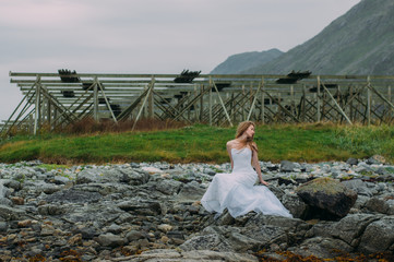 Fototapeta na wymiar Bride sitting on the stonein tide, fish dryers on background