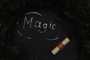 spruce branch, a small scroll and a bunch of decorative branches on a dark background with the...