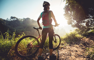 Fototapeta na wymiar Young woman cyclist enjoy the beautiful sunrise on summer forest trail