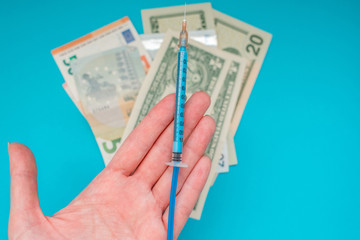 A hand giving vaccine syringe on the background of american dollar banknotes. Economy crisis. Health expense. Outbreak of coronavirus.