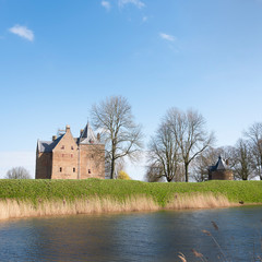 Fototapeta na wymiar castle loevestein and moat under blue sky in the netherlands near river waal