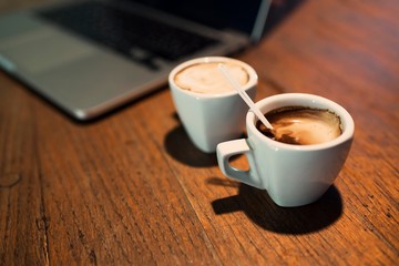 Side view of  modern laptop. Wooden table retro and two cup of coffee
