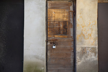 Old weathered locked wooden door with padlock