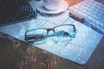 Financial chart hologram with glasses on the table background. Concept of business. Double exposure.
