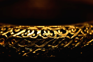 Gold color bracelet isolated on black background.