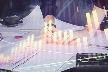Double exposure of man writing on paper with forex graph.