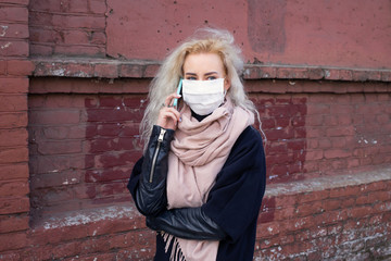 The girl is talking on the phone and walking around the city in a protective medical mask. Virus epidemic in the world