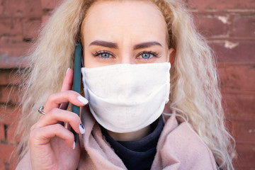 The girl is talking on the phone and walking around the city in a protective medical mask. Virus...