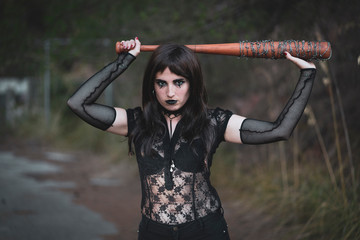 chica vestida de negro con el bate de The Walking Dead, en un descampado y diferentes poses para...