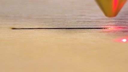 Machine for laser cutting wood close up cuts board and make straight line.