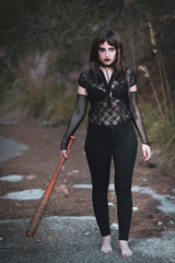 chica vestida de negro con el bate de The Walking Dead, en un descampado y diferentes poses para...