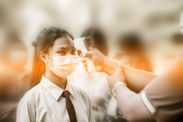 Asian people are being measured using a digital fever meter by government officials during the...