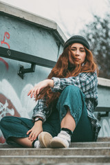 Image of a pleased happy cute young student curly girl sitting on bench outdoors