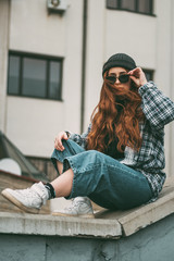 Image of a pleased happy cute young student curly girl sitting on bench outdoors