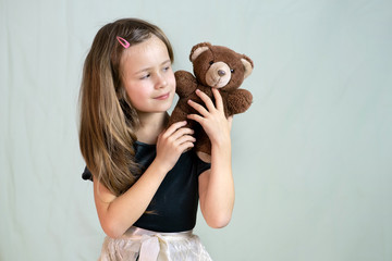 Pretty child girl playing with her teddy bear toy.