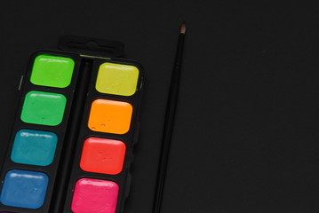 container with neon colors and a brush on a dark background