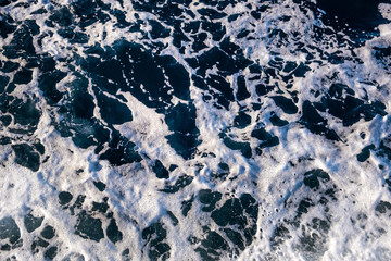 Top down aerial view of sea water surface. White foam waves texture as natural background.