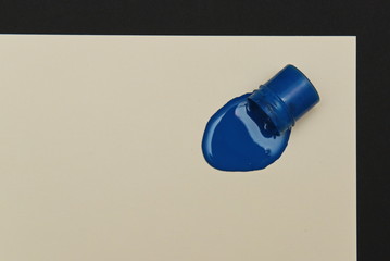 a can of blue gouache splashed onto the paper