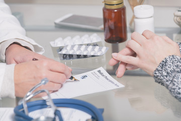 Doctor writes prescription to patient at worktable