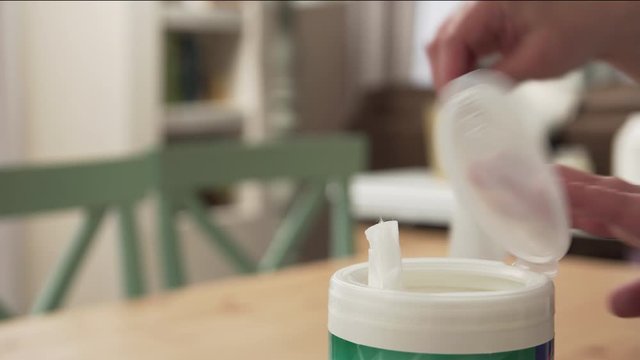 Close-up Of Woman Pulling Disinfecting Wipe From Container