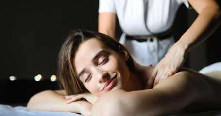 Happy woman relaxing receiving a massage in a spa salon