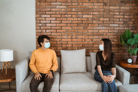 Man and woman wear face masks, sit apart, social distancing