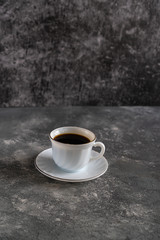 mug with black coffee on a saucer on a black background