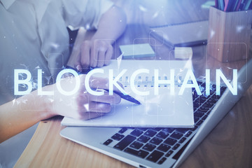 Cryptocurrency hologram, bitcoin, ico theme over hands taking notes background. Concept of...