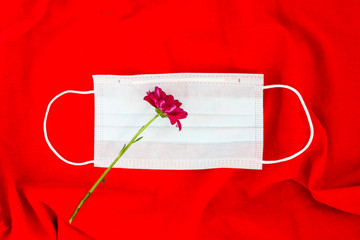 Flowers laying in the face mask on red background. Spring time allergy concept.
