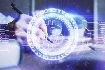 Cryptocurrency hologram, bitcoin, ico theme over hands taking notes background. Concept of...